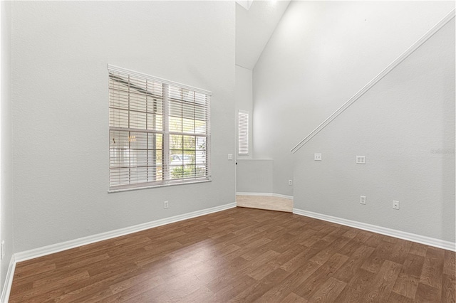 unfurnished room with dark wood-style floors, vaulted ceiling, and baseboards