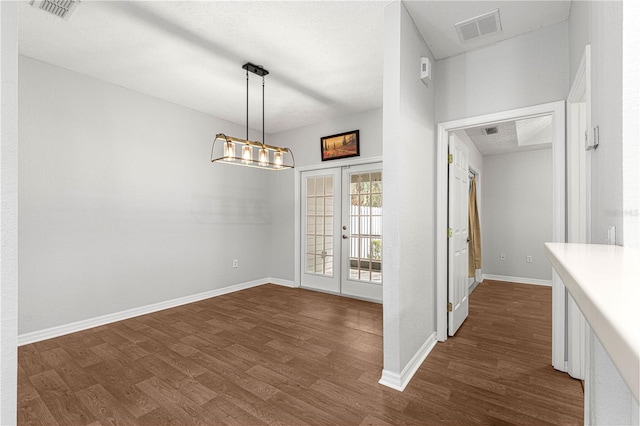 unfurnished dining area featuring dark wood-style floors, french doors, and visible vents