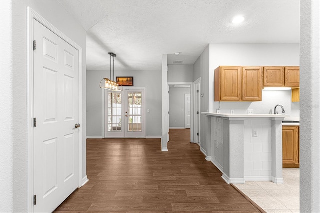 kitchen with french doors, light countertops, a textured ceiling, and wood finished floors