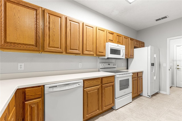 kitchen featuring a textured ceiling, white appliances, visible vents, light countertops, and brown cabinets