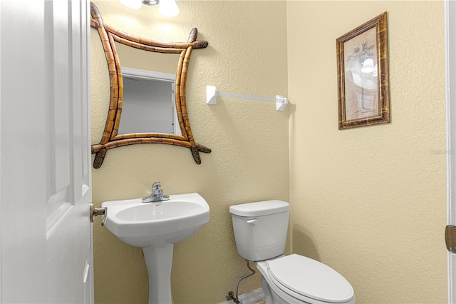 half bathroom featuring a textured wall and toilet