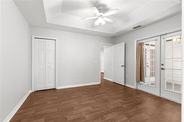 unfurnished bedroom featuring french doors, visible vents, a raised ceiling, and wood finished floors