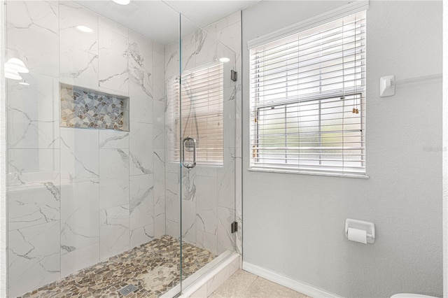 bathroom with baseboards, toilet, and a marble finish shower