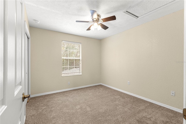 carpeted spare room with attic access, baseboards, a textured ceiling, and a textured wall