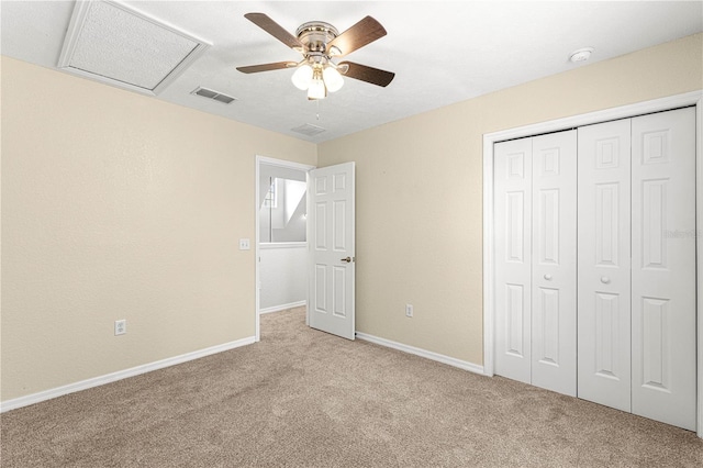 unfurnished bedroom featuring light colored carpet, visible vents, baseboards, a closet, and attic access