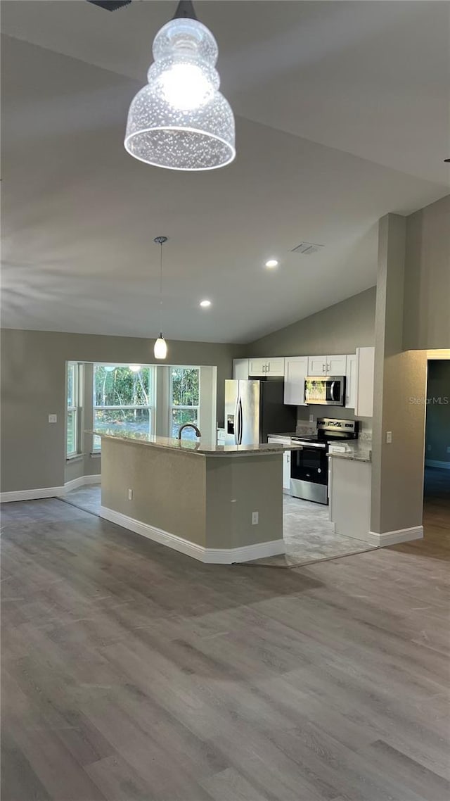 kitchen with white cabinets, vaulted ceiling, stainless steel appliances, light wood-style floors, and pendant lighting