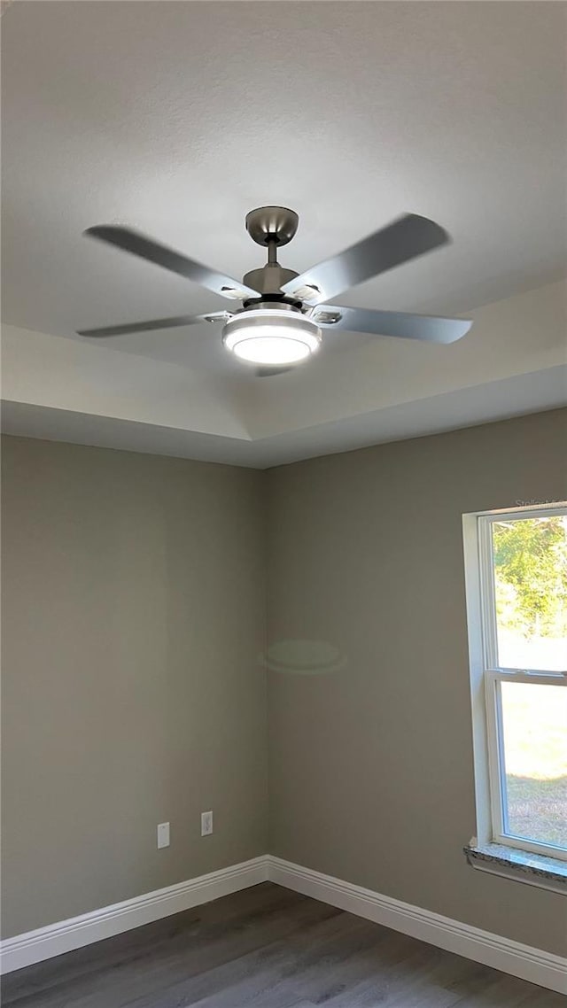 unfurnished room with a ceiling fan, dark wood-style flooring, and baseboards