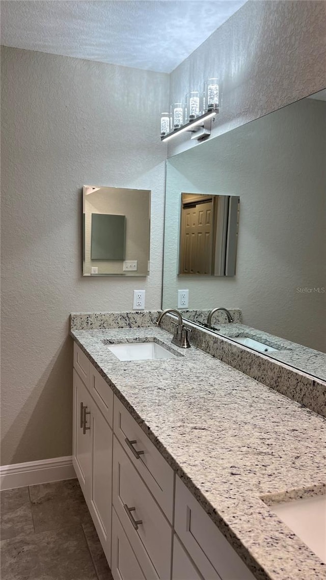 bathroom featuring a textured wall, vanity, and baseboards