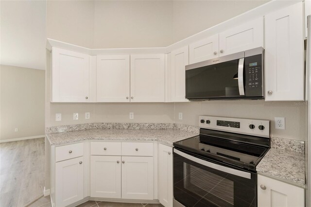 114 Bay Dr, Ocklawaha, FL 32179 - kitchen featuring stainless steel appliances, white cabinetry, light stone counters, light wood-style floors, and baseboards