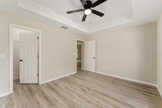 114 Bay Dr, Ocklawaha, FL 32179 - unfurnished bedroom with a tray ceiling, light wood-style floors, baseboards, a spacious closet, and a ceiling fan