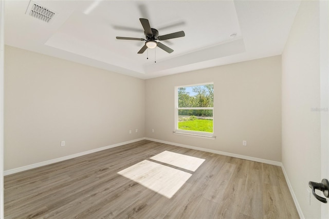 114 Bay Dr, Ocklawaha, FL 32179 - empty room featuring a tray ceiling, light wood-style flooring, ceiling fan, and baseboards