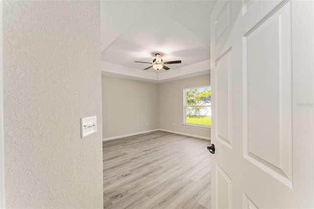 114 Bay Dr, Ocklawaha, FL 32179 - spare room with a tray ceiling, light wood-type flooring, a ceiling fan, baseboards, and a textured wall