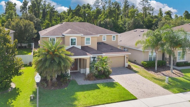 mediterranean / spanish-style home with decorative driveway, stucco siding, a front yard, fence, and a garage