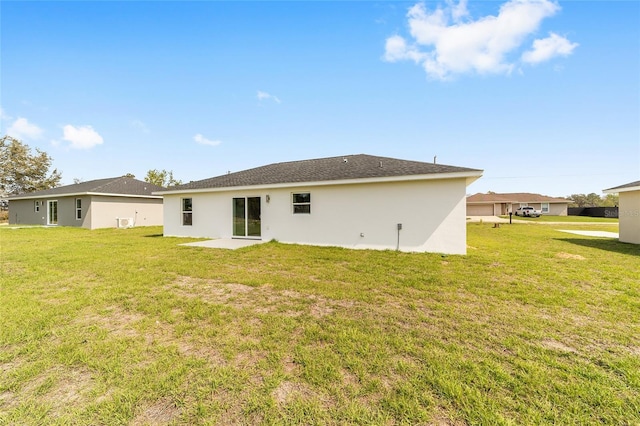 rear view of property with a yard and stucco siding