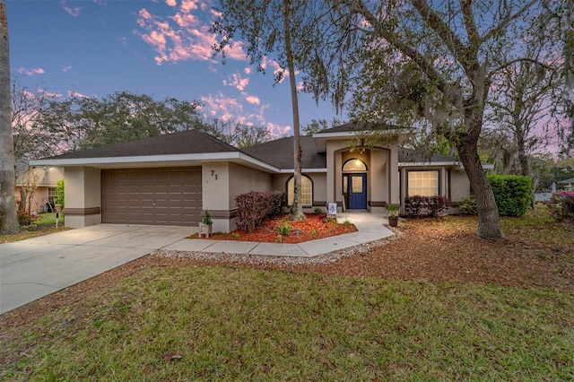 view of front facade with a garage, a front yard, driveway, and stucco siding