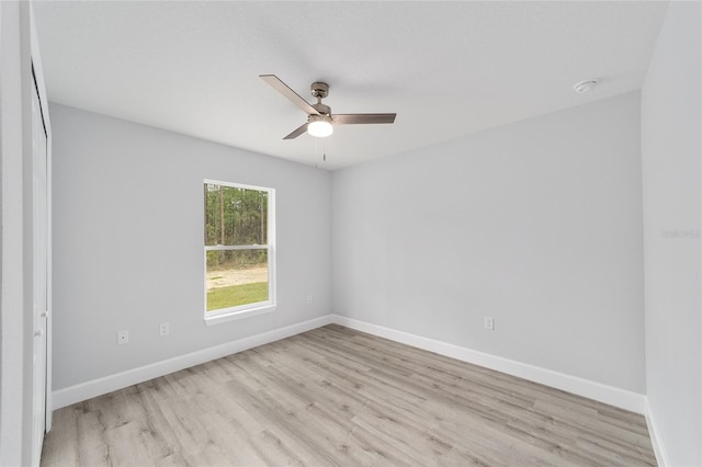 spare room with light wood-type flooring, a ceiling fan, and baseboards