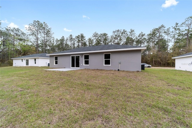 back of house featuring stucco siding, a lawn, and a patio