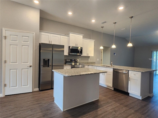 kitchen with white cabinets, appliances with stainless steel finishes, dark wood-style flooring, a peninsula, and a sink