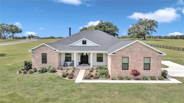 view of front of house featuring brick siding, roof with shingles, a porch, and a front yard