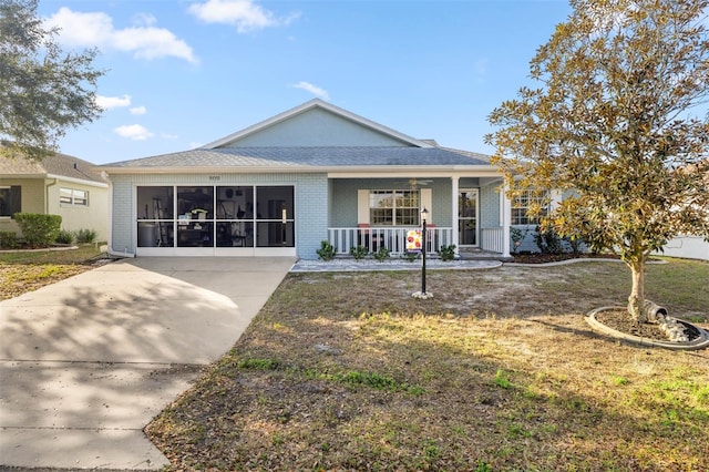 view of front of house with a sunroom, a front yard, covered porch, and brick siding