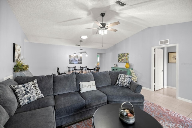 living room featuring lofted ceiling, visible vents, a textured ceiling, and light tile patterned floors