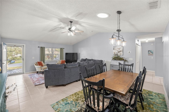 dining space featuring a textured ceiling, light tile patterned flooring, visible vents, baseboards, and vaulted ceiling