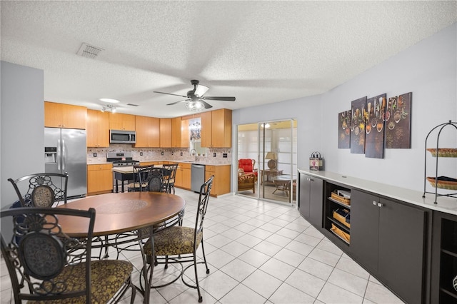 dining room with light tile patterned floors, a textured ceiling, visible vents, and a ceiling fan