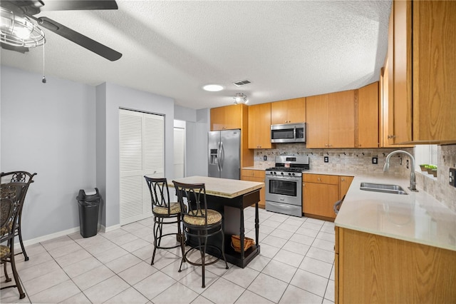 kitchen featuring tasteful backsplash, visible vents, appliances with stainless steel finishes, light countertops, and a sink