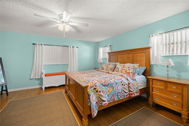 bedroom with dark wood-style floors, ceiling fan, a textured ceiling, and baseboards