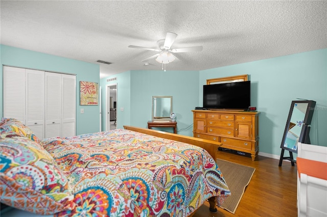 bedroom featuring a textured ceiling, wood finished floors, visible vents, baseboards, and a closet