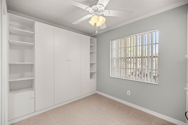 unfurnished bedroom with a textured ceiling, ceiling fan, baseboards, a closet, and crown molding