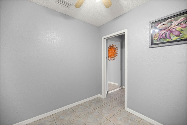 unfurnished room featuring light tile patterned floors, a textured ceiling, visible vents, baseboards, and a ceiling fan