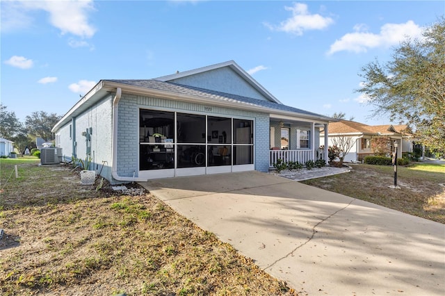 view of front of property featuring a sunroom, central AC unit, and brick siding