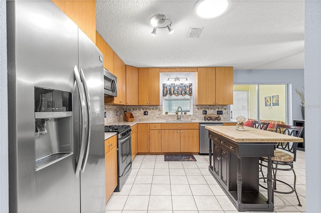 9770 SW 97th Pl, Ocala, FL 34481 - kitchen featuring appliances with stainless steel finishes, a sink, a textured ceiling, light countertops, and a kitchen bar