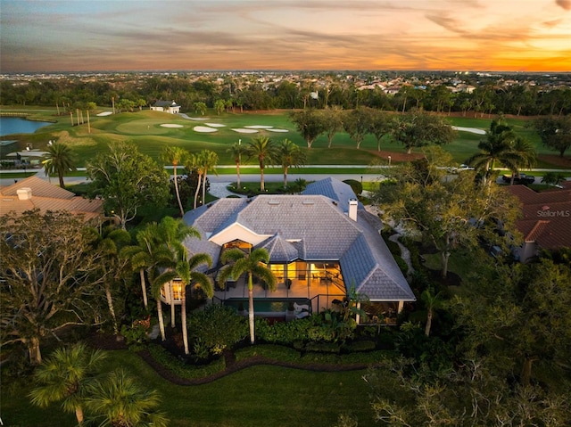 aerial view at dusk featuring golf course view and a water view