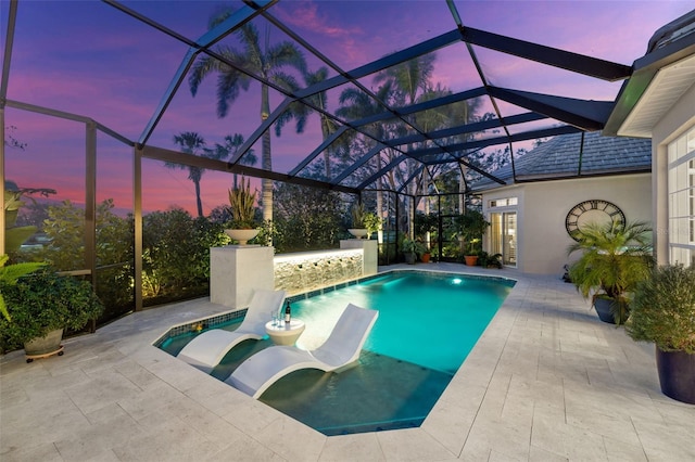 pool at dusk featuring a patio area, a lanai, and an outdoor pool