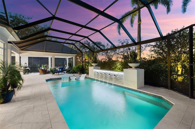 pool at dusk with an outdoor pool, a patio, and a lanai