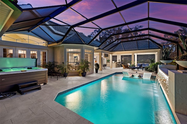 pool at dusk with an outdoor pool, a patio area, a lanai, and a hot tub