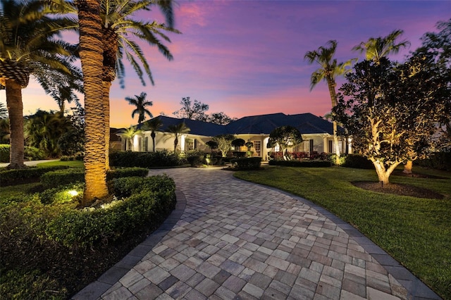 view of front of property with decorative driveway and a yard