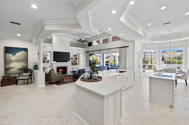 kitchen with light tile patterned floors, a warm lit fireplace, a sink, and a center island