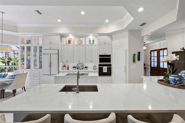 kitchen featuring paneled fridge, a sink, visible vents, and a breakfast bar area