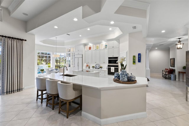 kitchen featuring a sink, light countertops, a large island, black appliances, and a raised ceiling