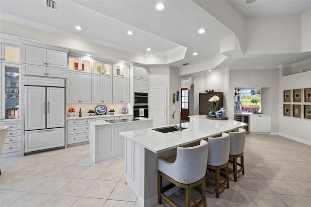 kitchen with paneled built in fridge, a spacious island, visible vents, and a sink