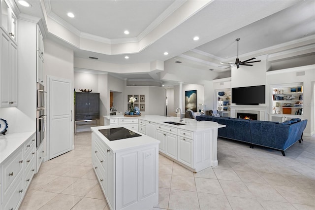 kitchen featuring a raised ceiling, a sink, a large island, and black electric cooktop