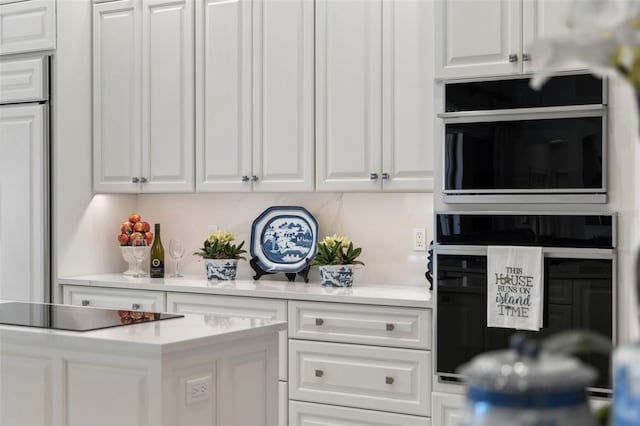 kitchen with black appliances, white cabinetry, and light countertops