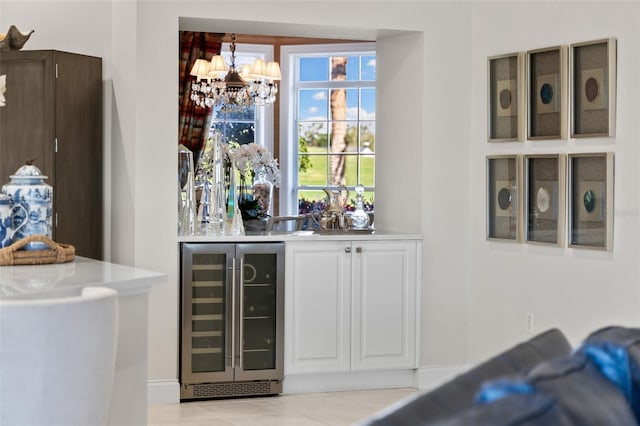 bar with light tile patterned floors, beverage cooler, and a chandelier