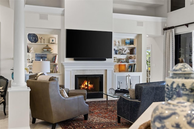 living room with a warm lit fireplace, visible vents, decorative columns, and built in features