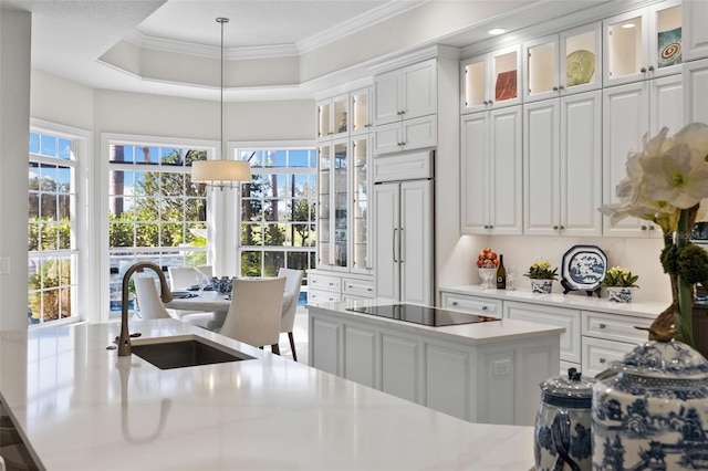 kitchen featuring ornamental molding, paneled built in refrigerator, a tray ceiling, black electric stovetop, and a sink