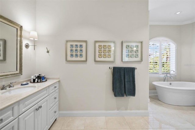 full bathroom with a freestanding tub, baseboards, ornamental molding, and vanity