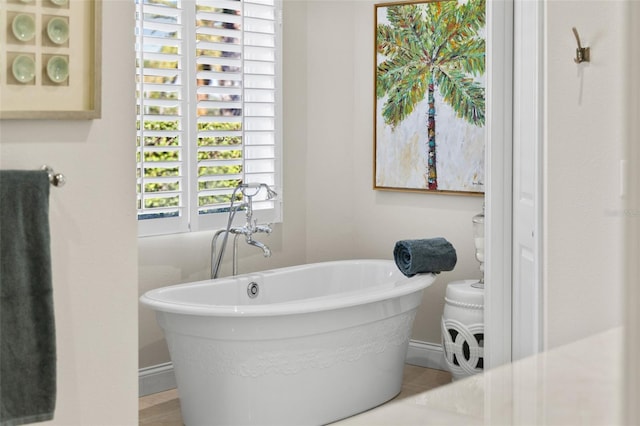 full bathroom featuring a soaking tub and baseboards